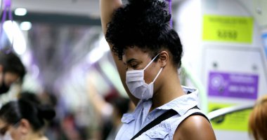 Metro tırabzanı tutan bir kadın. Kovid-19 yüz maskesi takıyor.