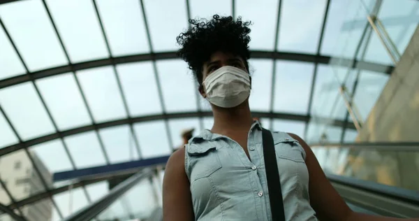 Woman commuting to work wearing pandemic face mask descending elevator