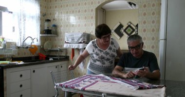 Karı koca cep telefonu ekranını kontrol etmek için arıyor. Son sınıf evli çift ev mutfağında.