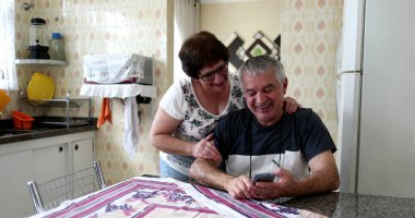 Mutfakta cep telefonuna bakıp gülümseyen mutlu evli çift.