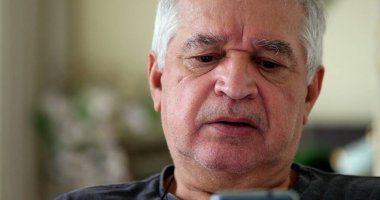 Evde cep telefonu kullanırken hayal kırıklığına uğramış bir ihtiyar. Akıllı telefona bakan yaşlı kişi üzgün.