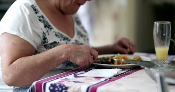 Senior woman eating lunch, casual older person at kitchen eating meal