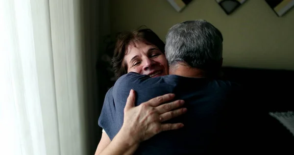 Older married couple embracing each other at home. Senior husband showing empathy and support with wife