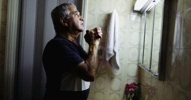 Yaşlı adam elinde haç işareti ile af diliyor.