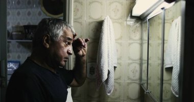 Orta yaşlı bir adam aynanın önünde kriz geçiriyor.