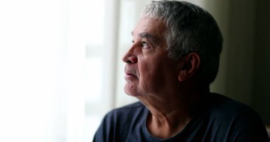 Bunalımda olan orta yaşlı bir adam evde oturup pencereden bakıyor.