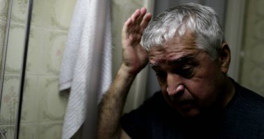Bunalımda olan yaşlı bir adam kriz anında banyo aynasına bakıyor.