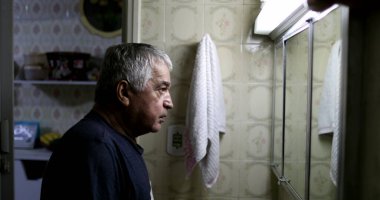 Sıradan yaşlı bir adam banyo aynasında kendine bakıyor.