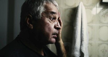 Yalnızlık ve hastalık içinde banyodaki aynanın önünde acı çeken son sınıf öğrencisi.