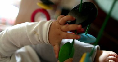 Bebek elleri asılı oyuncaklara dokunuyor, bebek oyuncakları aktivitesi yapıyor.