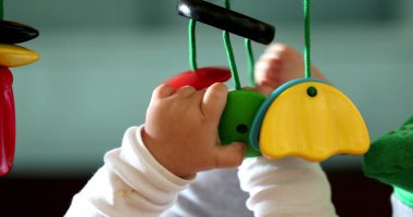 Bebek elleri oyuncak tutuyor, çocuk geliştirme oyuncaklarıyla yakın plan bebek oyunları oynuyor.