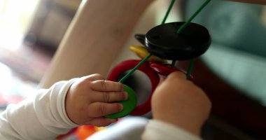 Bebek elleri asılı oyuncaklara dokunuyor, bebek oyuncakları aktivitesi yapıyor.