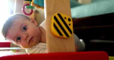 Bebek yerde oyun hasırının üzerinde yatar çorap bezini ağzına koyar, çocuk gelişimi