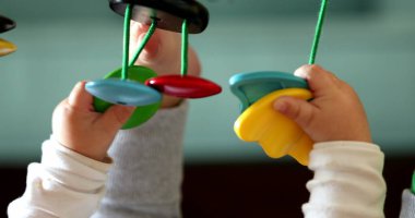 Bebek elleri oyuncak tutuyor, çocuk geliştirme oyuncaklarıyla yakın plan bebek oyunları oynuyor.