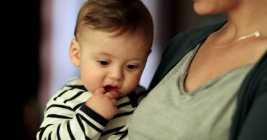 Bebek kucağında anne kolyesi. Annesi kucağında bebekle geziyor.