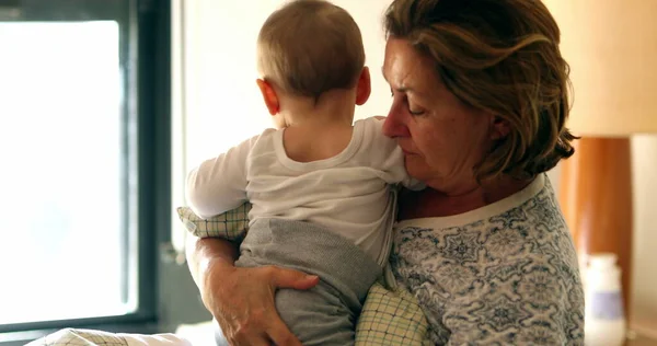 Candid family moment, grand-mother with baby grandson in bed morning