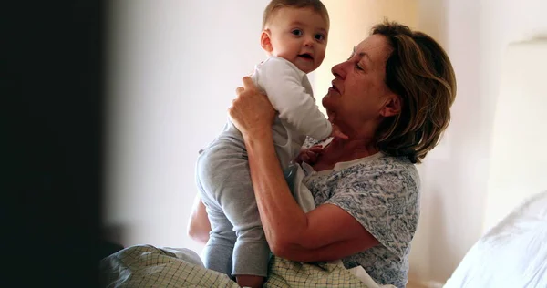 Candid family moment, grand-mother with baby grandson in bed morning