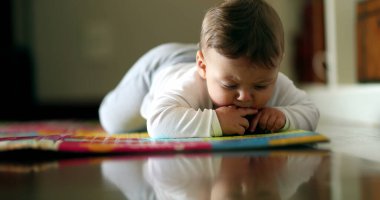Bebek oturma odasında yerde sürünmeyi öğreniyor. Şirin bebek cilt kavrama nesnesi