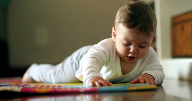 Bebek oturma odasında yerde sürünmeyi öğreniyor. Şirin bebek cilt kavrama nesnesi