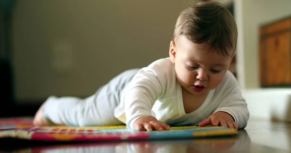 Baby learning to crawl in living-room floor. Cute toddler infant cild grabbing object