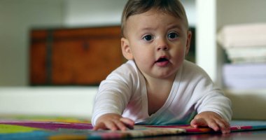 Yerde uzanmış oyun halısına dokunan tatlı bir bebek.