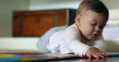 Yerde uzanmış oyun halısına dokunan tatlı bir bebek.