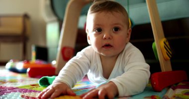 Sevimli bebek çocuk gelişimi evde oyun paspasında emeklemeyi öğreniyor.