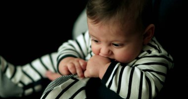 Pijama giyen şirin bir bebek ayaklarını ağzına sokuyor. Sevimli bebek sevimli oluyor.