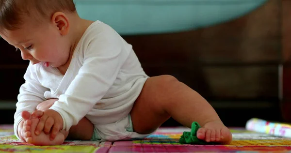 可爱的幼儿在玩具垫子上想咬自己的脚 — 图库照片