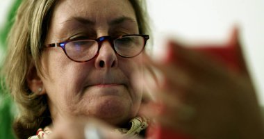 Yaşlı kadın geceleri cep telefonu kullanıyor. Üst düzey kişi akıllı telefon ekranı okuyor, sıradan ve otantik.