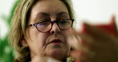 Yaşlı bir kadın cep telefonu cihazı tutuyor. Üst düzey bir bayan ekran okumasına bakıyor.