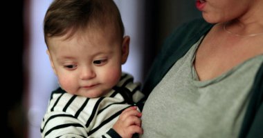 Anne konuşurken bebeği evde rastgele tutuyor. Ebeveyn, bebeğini kucağına alır