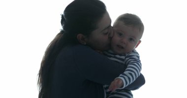 Anne ve bebeği öpmek. Anne kucağında bebekle ilgilenirken yanağından öpüyor.