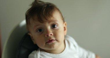 Kameraya gülümseyen sevimli bir bebek. Sandalyeye oturan erkek bebeğin portresi.