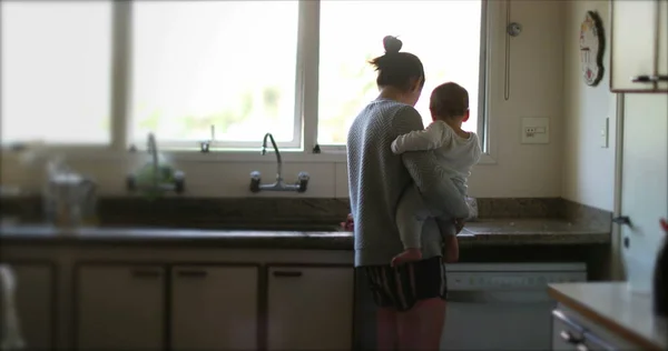 临时妈妈抱着孩子在厨房多任务 家长在家里清洁婴儿 — 图库照片