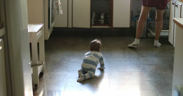 Ehrliches Baby Krabbelt Auf Küchenboden Während Großmutter Hausfrau Macht — Stockfoto