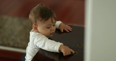 Evde mobilyalarla oynayan şirin bir bebek.