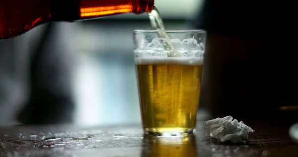 Pouring beer with bottle inside glass close-up