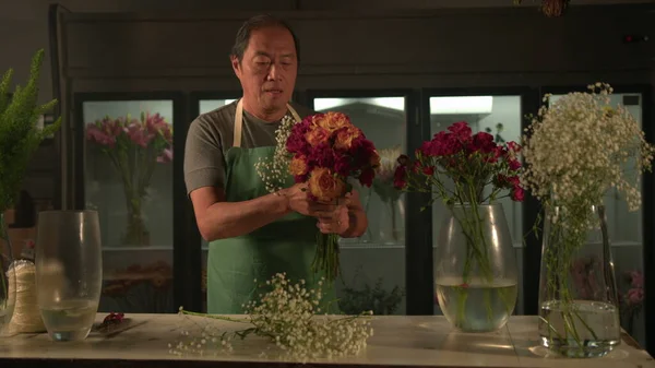 Florist creating beautiful bouquet flowers inside flower shop local business