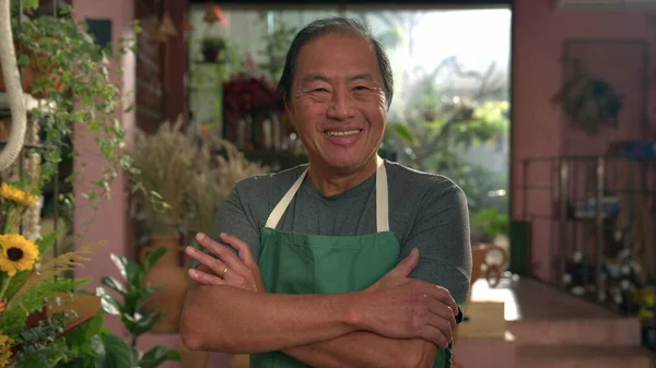 Portrait of a male Asian employee at flower shop. Local small business staff wearing apron smiling