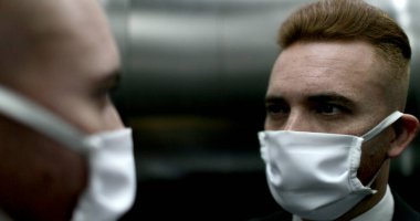 Cerrahi maske takan, yüzünü parmaklarıyla ovuşturan bir adam.