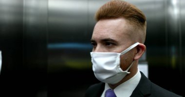 Asansör aynasının içine yüz maskesi takan bir adam. Dışarı çıkmak için CV19 cerrahi maske takan biri.