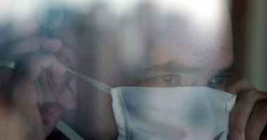 Camdan yansıyan camla görülen kişi CV19 cerrahi maskeli.