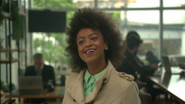 Bir bayan müşteri kahve tezgahında sırıtarak siparişin gelmesini bekliyor.