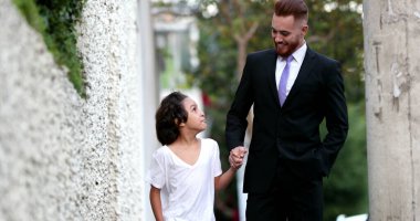 Güzel baba ve melez oğul şehir kaldırımında birlikte yürüyorlar, ebeveyn ve etnik çeşitlilikte genç çocuk kaynaşıyor.