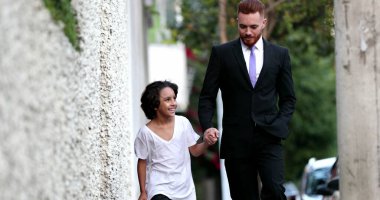 Güzel baba ve melez oğul şehir kaldırımında birlikte yürüyorlar, ebeveyn ve etnik çeşitlilikte genç çocuk kaynaşıyor.