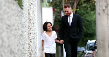 Güzel baba ve melez oğul şehir kaldırımında birlikte yürüyorlar, ebeveyn ve etnik çeşitlilikte genç çocuk kaynaşıyor.