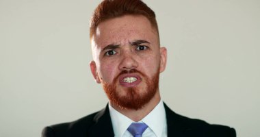 Kızgın adam kameraya konuşuyor, İrlandalı görünüşlü biri tartışıyor.