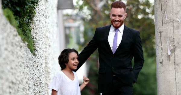 Güzel baba ve melez oğul şehir kaldırımında birlikte yürüyorlar, ebeveyn ve etnik çeşitlilikte genç çocuk kaynaşıyor.