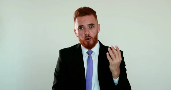 Angry man protesting looking at camera in argument. Upset person wearing business suit talking to camera